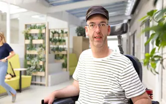 Man in rolstoel met petje in gang naar P