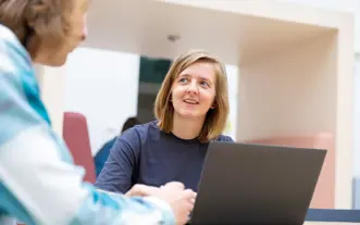 Vrouwelijke student aan tafel atrium met laptop