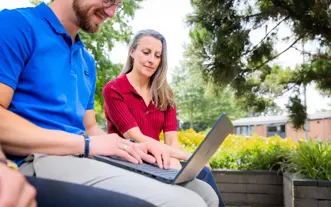 Man laptop op schoot plus vrouw