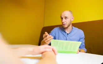 Man uitleg met boek in treinzitje