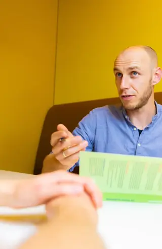 Man uitleg met boek in treinzitje