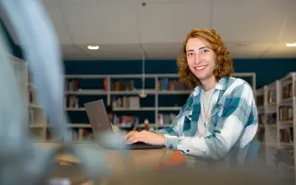 Jongen met neusring achter laptop in studiecentrum