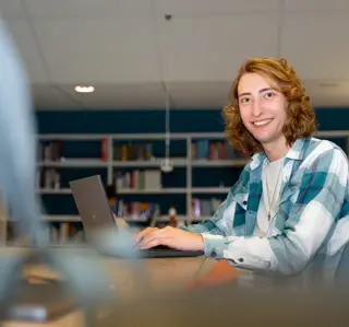 Jongen met neusring achter laptop in studiecentrum