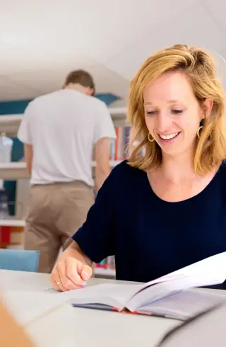 Jonge vrouw korter blond haar studerend in studiecentrum
